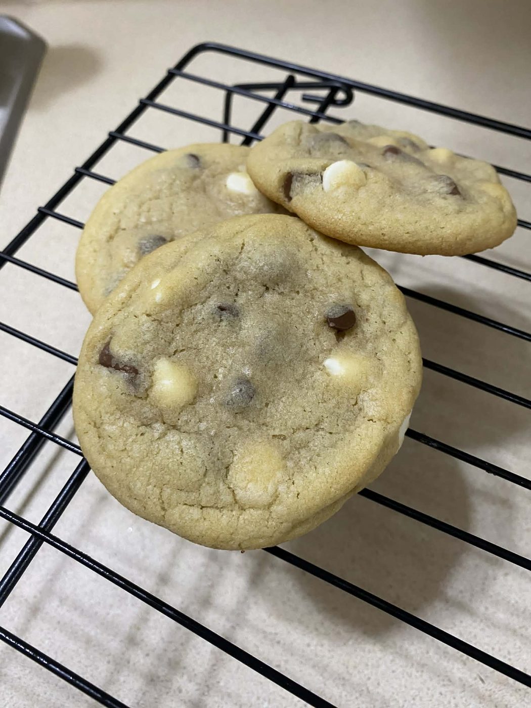 Triple chocolate cookies with white and dark chocolate chips on a cooling rack